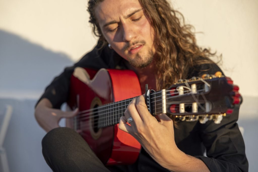 Guitarrista flamenco tocando una guitarra española con intensidad y concentración durante una puesta de sol