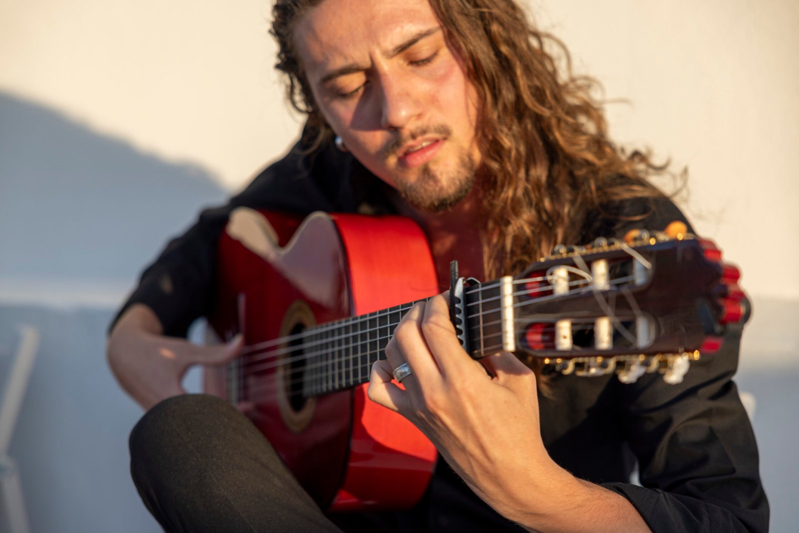 Guitarrista flamenco tocando una guitarra española con intensidad y concentración durante una puesta de sol