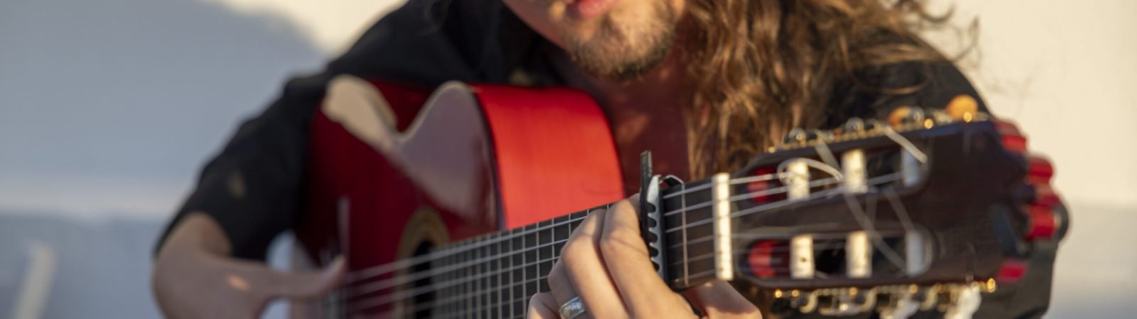Guitarrista flamenco tocando una guitarra española con intensidad y concentración durante una puesta de sol